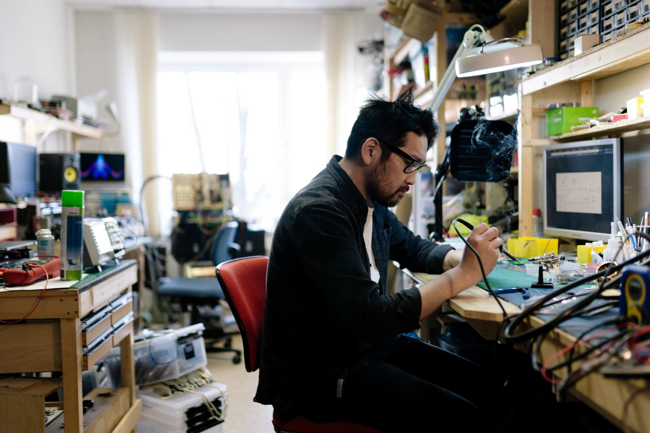 Engineer soldering electronics in a small workshop